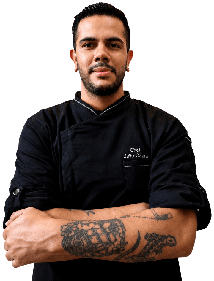 Julio Cabral usando uniforme preto de chef, com os braços cruzados.